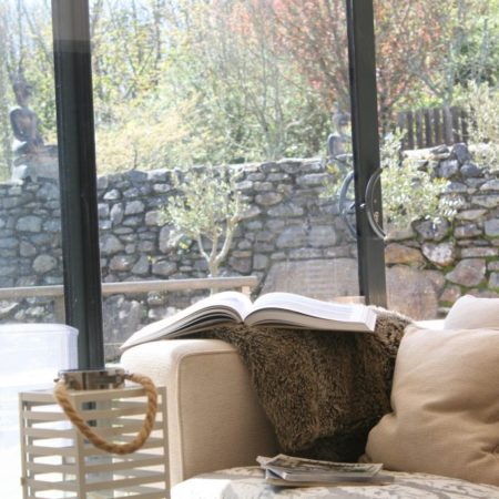 Comfortable sofa with Book & Blanket, large patio door and garden in the background